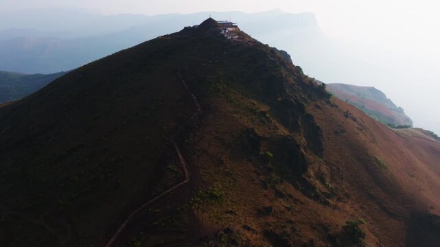 zig zag stairs on Mullayanagiri peak with hill top temple and fog at Western Ghats, Chikkamagaluru, karnataka, india. day time, arc shot, drone shot, 4k.