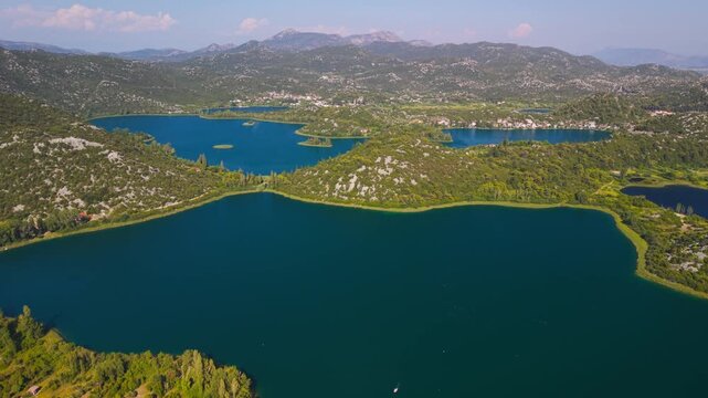 Panoramic aerial view of the vibrant blue Bacina Lakes surrounded by green karst hills near Ploce, Croatia