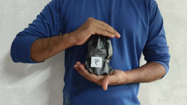 Closeup of person hand protecting Indian rupee money bag inside palm. Insurance of capital, deposits, business and savings accounts. Guaranteed payments protection and financial security concept.