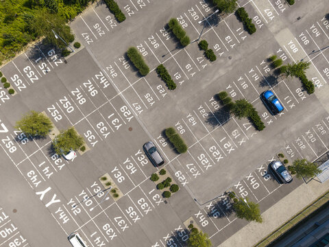 Aerial view of a parking lot with numbered spaces, green bushes, and parked cars in Krakow, Lesser Poland Voivode, Poland.
