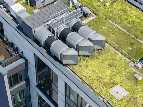 Aerial view of mechanical ventilation units installed on a modern green roof with lush vegetation in Krakow, Poland.