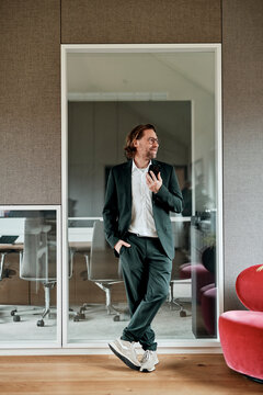 Smiling businessman holds a smartphone in a modern office