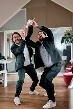 Two businessmen celebrate a victory with a trophy in the office