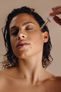 Model applying facial oil serum for glowing skincare