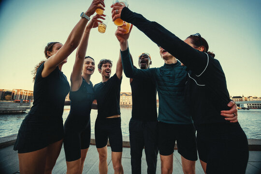 Running friends celebrate with beer after run club by the water