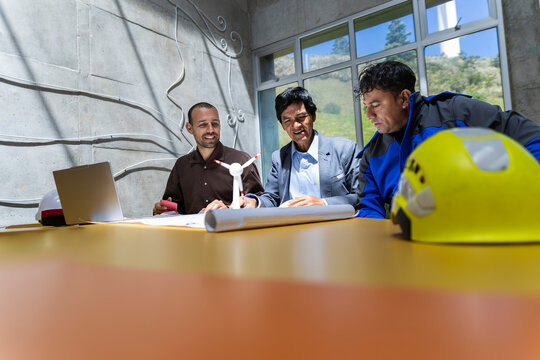 Team of engineers checks a wind farming blueprint in an office