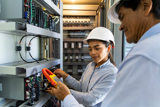 Man and woman engineers measuring electricity at indoor facility