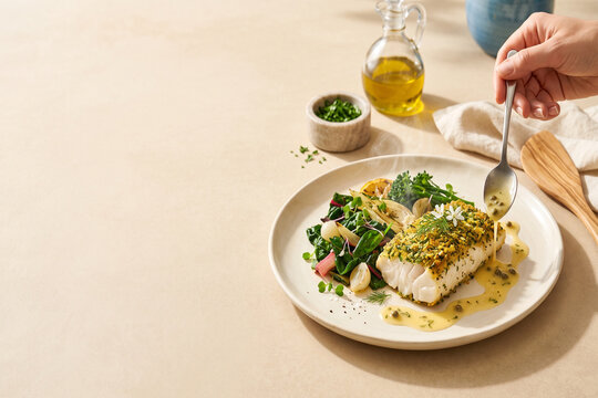 Herb-crusted baked white fish fillet, hand spooning caper butter sauce, roasted greens, restaurant menu cover