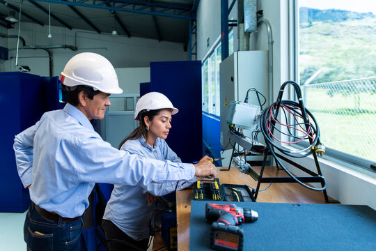 Mentor teaching apprentice industrial skills at indoor wind farm