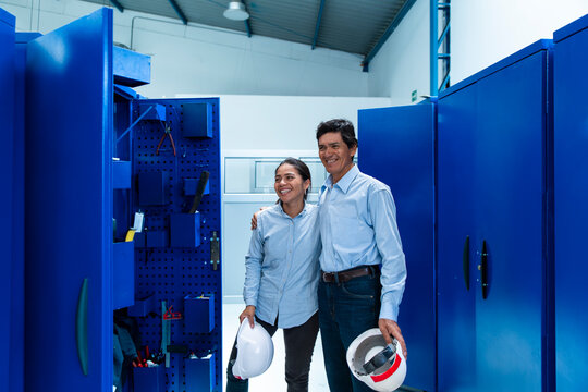 Male and female technician coworkers laugh in a locker room after work