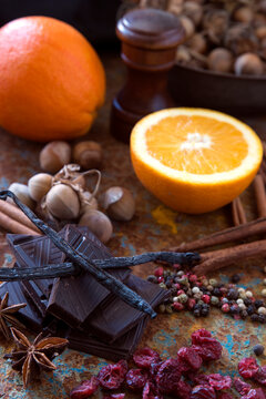 Close-up of dark chocolate, fresh oranges  and assorted spices on a wooden table