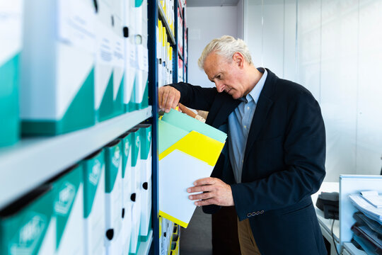 A businessman searches for a document in the office archive