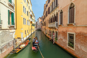 Gondola Carrying Tourists Through a Historic Canal in Venice, Italy © roobcio