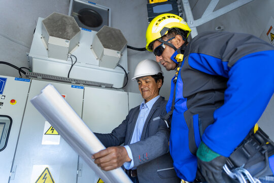 Engineer and technician examine a blueprint in a wind turbine base