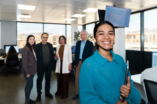 Smiling businesswoman holds a laptop with her team in the office