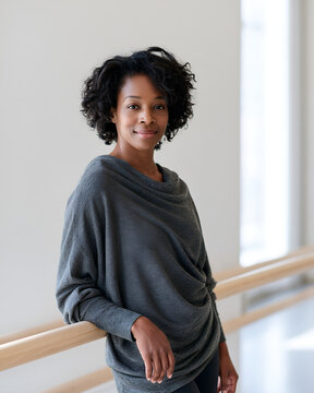 Portrait of a dance teacher beside the barre in a bright studio