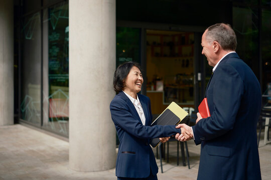 Businessman and businesswoman shake hands outside
