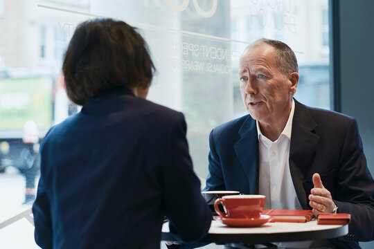 Businessman and businesswoman discuss reports in a coffee shop