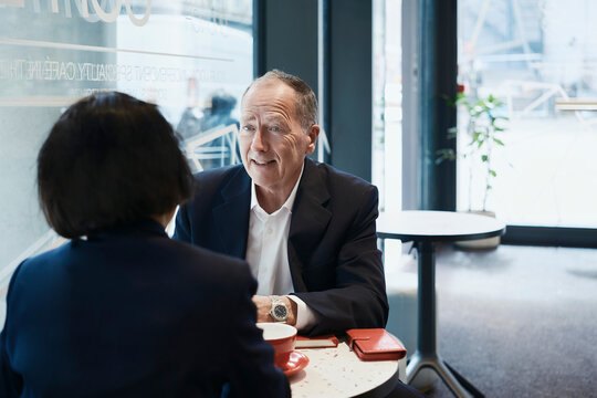 Businessman talks with female colleague at a coffee shop