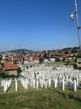 Aerial view of Kovaci Martyrs Cemetery with rows of white tombstones set against the backdrop of historic red-tiled rooftops, Sarajevo, Federation of Bosnia, Bosnia and Herzegovina.