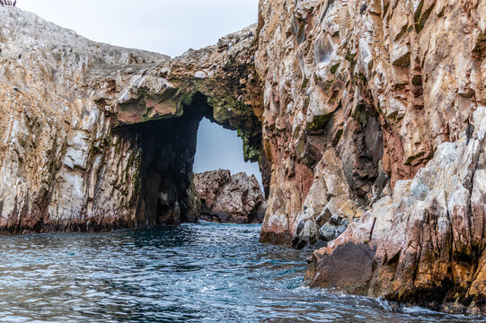 A view from a tourist boat towards a rocky arch in the Ballestas Islands, Paracas, Peru in the dry season