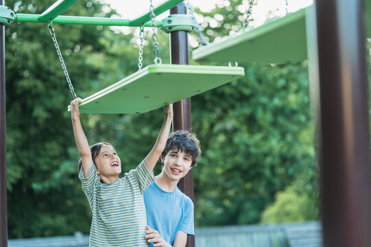 Older brother helps boy on an obstacle course at the playground
