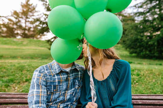 Young couple kissing behind green balloons