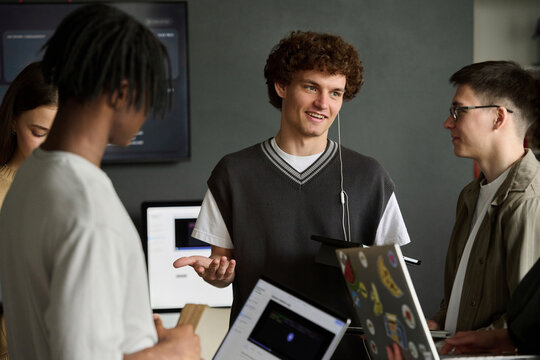 Smiling student discusses class work with a man and woman indoors