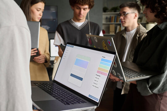Group of students looking at app design on a laptop in class