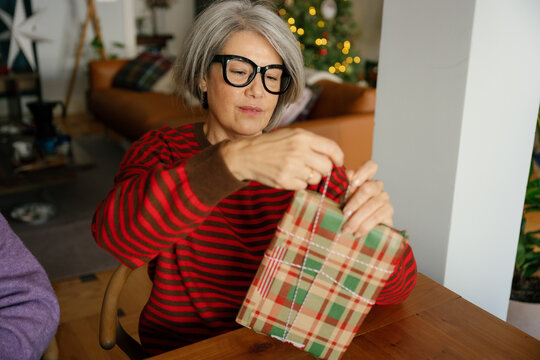 Mother and daughter wrapping a Christmas present together indoors