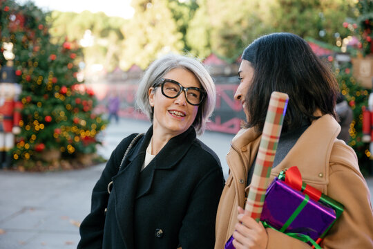 Mother and daughter talk and hold a Christmas gift outdoors