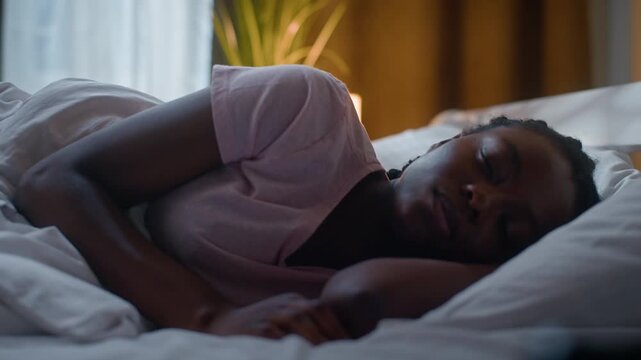 Unhappy African American woman lying in bed awake at night unable sleeping suffering insomnia discomfort female tired girl turning side under blanket bedroom sleepless problem sleep health disorder