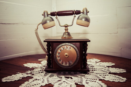Old telephone standing on crochet tablecloth in a corner