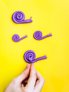 Hand putting heart on snail family made from modelling clay