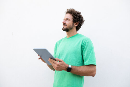 Smiling young man uses tablet against white background