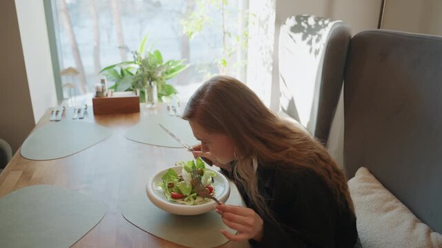 White woman hesitating over salad at table, diet dilemma unfolding in slow gestures, tasting attempt followed by pause, sunlit restaurant corner, fashionable jacket, leafy bowl, introspective