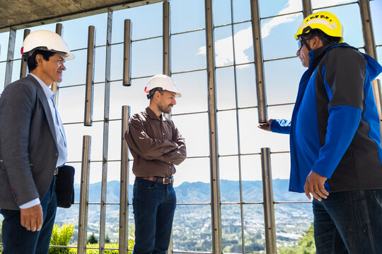 Male coworkers discuss infrastructure at a sunny site in Loja Ecuador