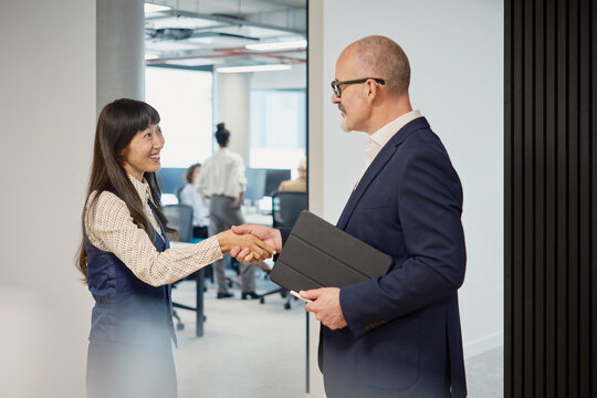 A businessman and a businesswoman shake hands during an interview