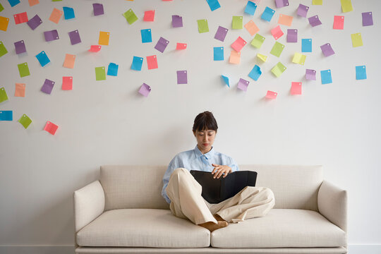 Woman works on tablet computer on couch in office