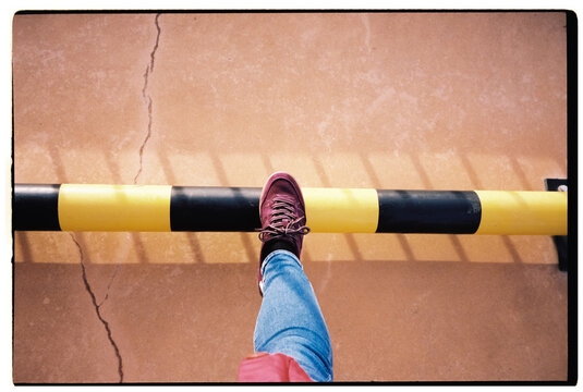A person steps over a striped caution barrier outdoors