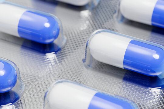 Blue and white medicine capsules rest inside a foil blister pack