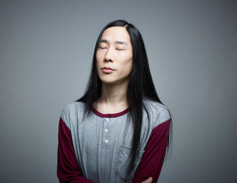 Mid adult man with eyes closed against grey background, close up