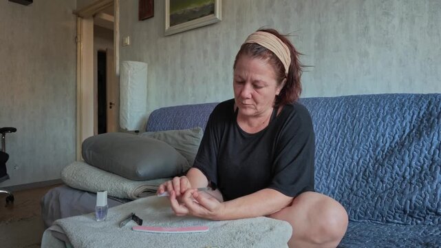 Woman Trimming and Filing Her Nails During Manicure at Home Today