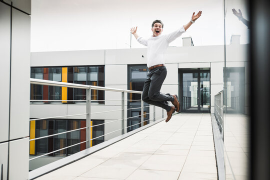 Cheering businessman jumping on skywalk at office building