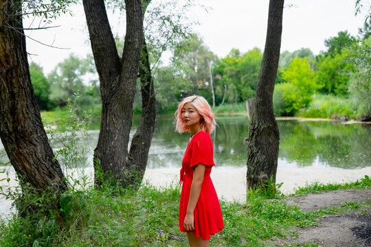 Woman wears a red dress by the river