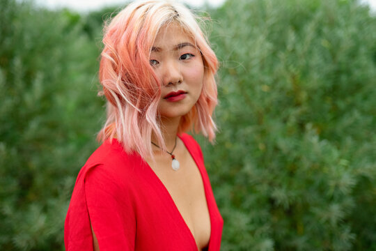 Woman with red hair wears a red dress outdoors in a summer field