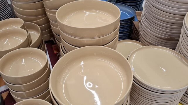 ceramic bowls and plates stacked in a market display, kitchenware shopping, home dining, neutral tones, retail selection, household goods, practical living.