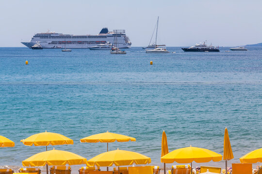 France, Cote d'Azur, Cannes, beach umbrellas on beach and cruse ship on the ocean