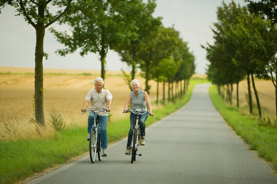 Senior couple biking on country road