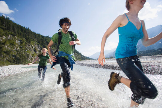Germany, Bavaria, T�lzer Land, Young people running through river